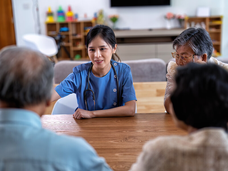 Professional nurse providing companionship and social interaction with elderly clients in comfortable home environment