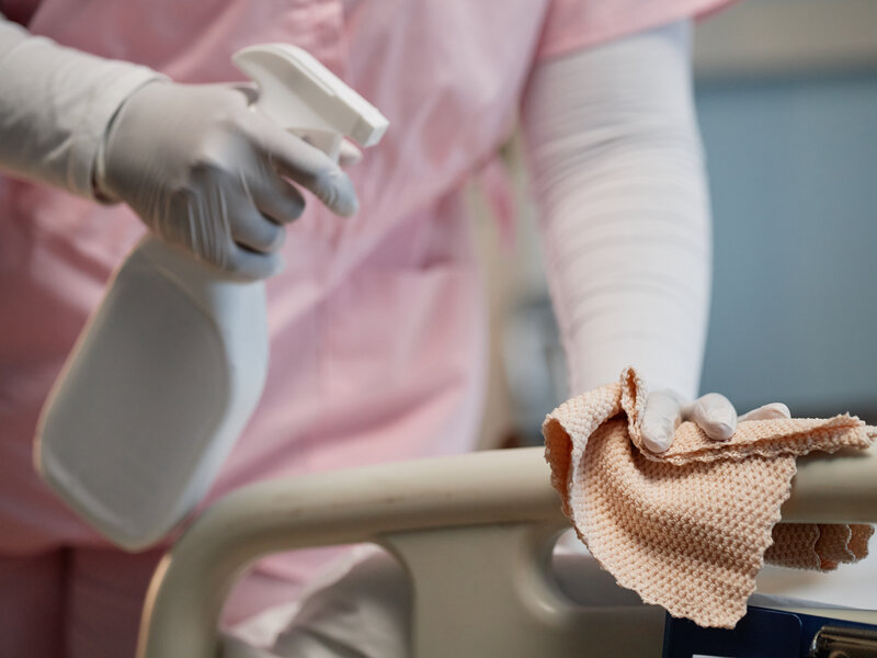 Professional healthcare worker maintaining hygiene and infection control standards while cleaning medical equipment