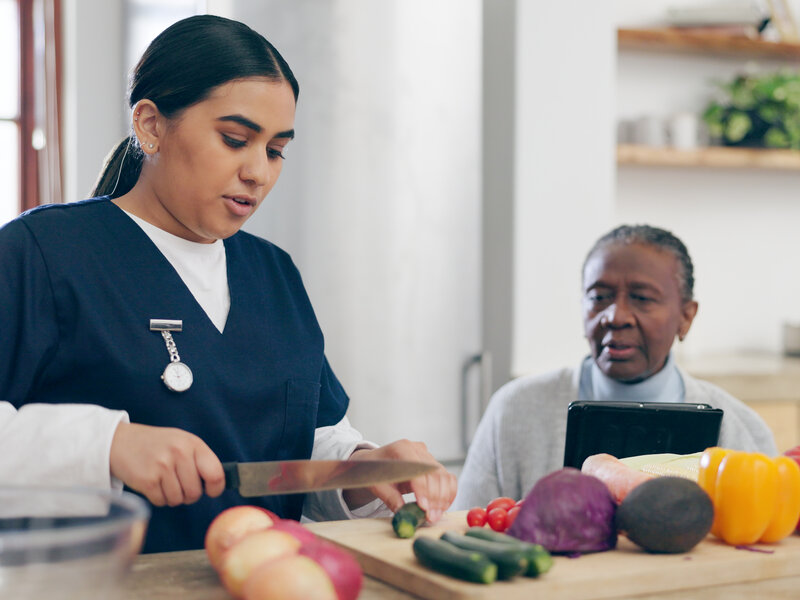Professional nurse preparing healthy meals with elderly client in modern, well-equipped kitchen