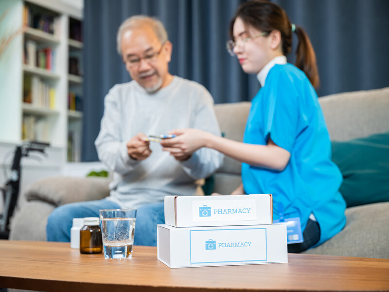 Professional nurse showing medication to elderly patient in comfortable home setting