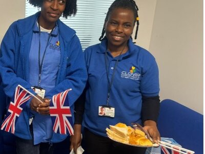Tea Party May 2024 - Two team members celebrating with Union Jack flags and traditional British treats